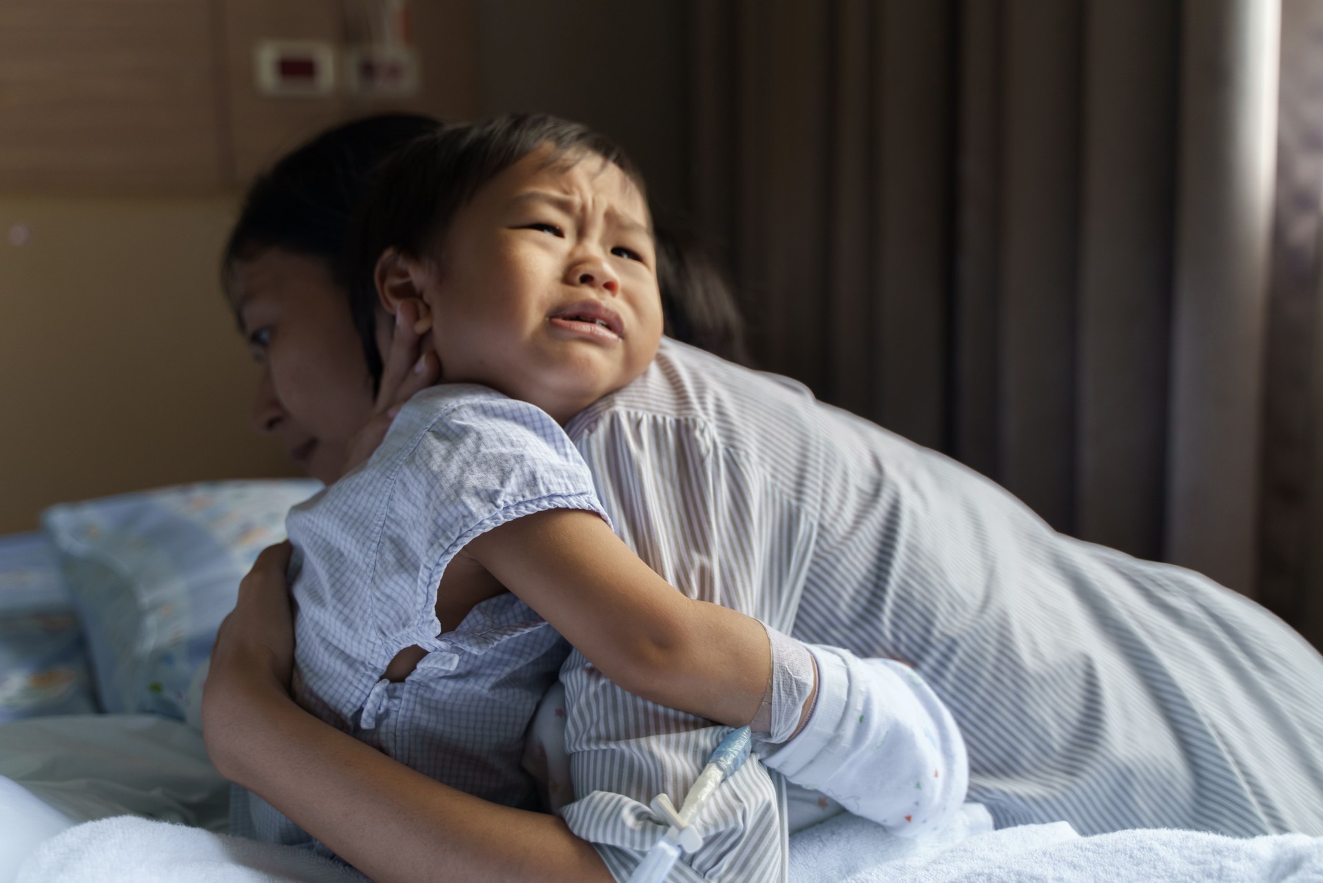 Asian mother taking care of sick little son in hospital.