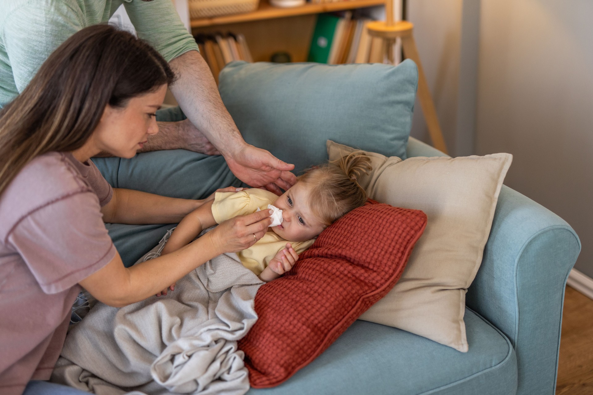 Parents caring for their sick daughter on the couch